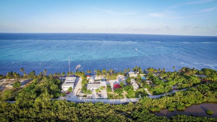El inmueble desde el aire: la línea de arrecife mar adentro, el conjunto en la playa, manglar detrás
