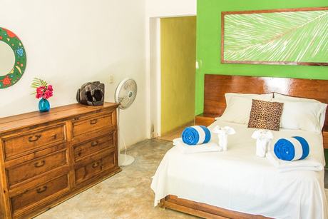 Una habitación, con cama y cómoda de madera